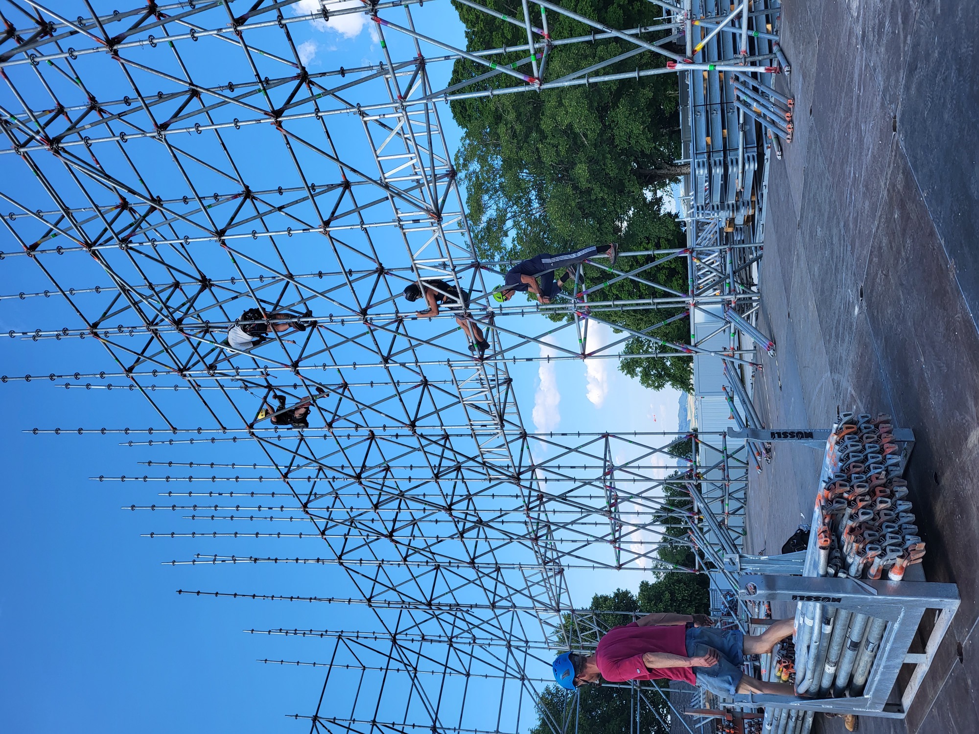 Crew arbeitet im Gerüst vor blauem Himmel